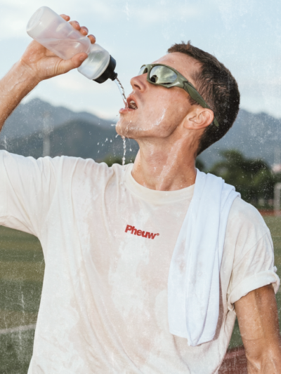 Person drinking water outdoors with mountains in the background